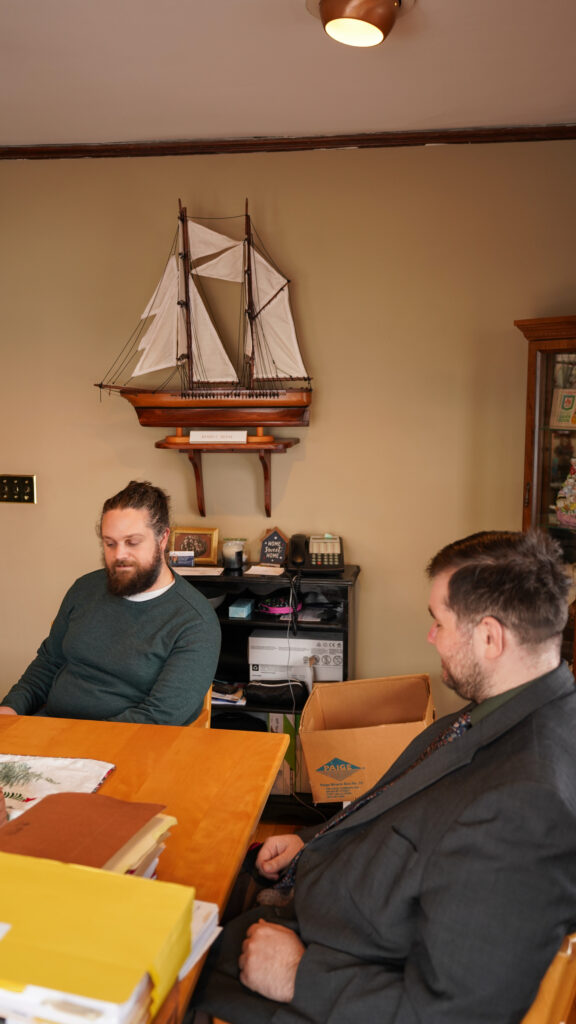 Two young professionals working together at a desk with multiple laptops and a tablet